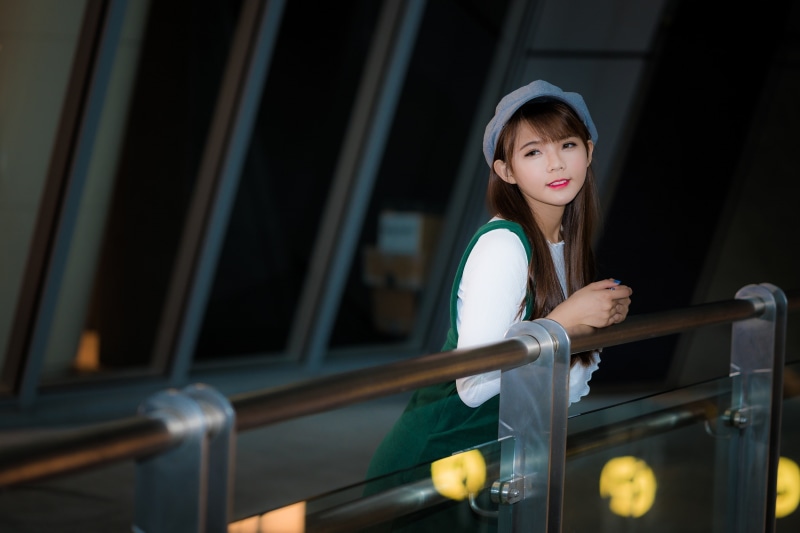 hairstyle, looking at camera, casual clothing, depth of field, standing, women, young adult, railing, one person, architecture, looking away, beautiful woman