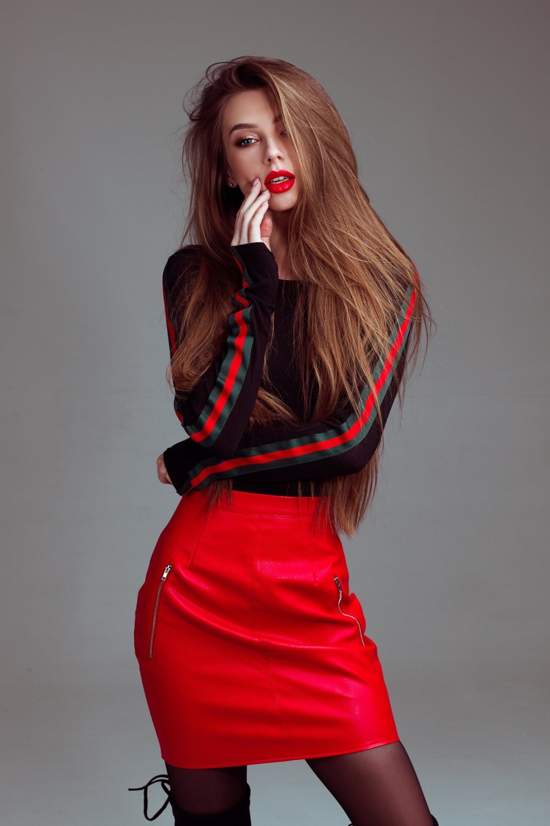 looking at viewer, hairstyle, gray background, indoors, beautiful people, red, red skirt, one person, fashion, beauty, women, luxury, beautiful woman, fashion model