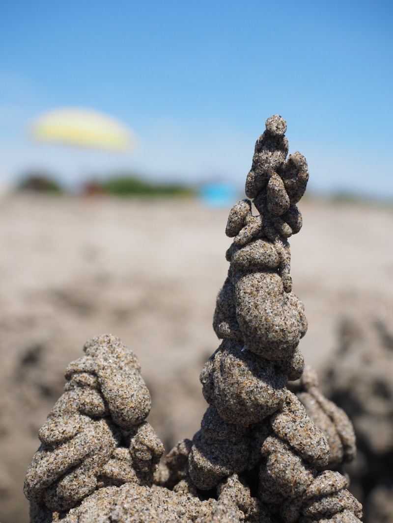 balance, stone - object, build, sandalwood, outdoors, focus on foreground, drip castle, sunlight, sea, clear sky, land, textured, relax, artwork, no people
