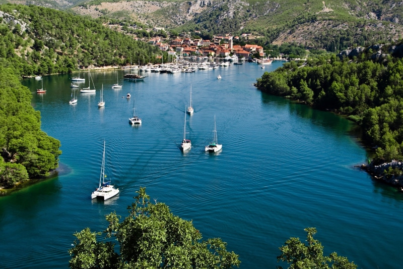 vacation, mode of transportation, green, harbor, high angle view, lake, surrounded, landscape, no people, summer, body, building exterior, beauty in nature
