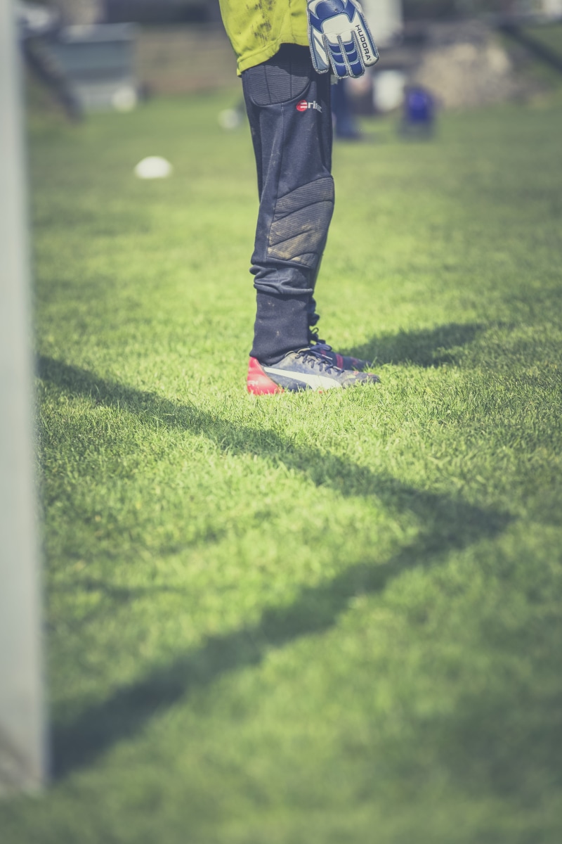 kicker, leisure activity, ball game, shoot, door husband, grass, day, keeper, goalkeeper, golf club, football pitch, sunlight, parade, 5K, human leg, soccer shoes