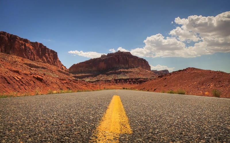 dividing line, direction, double yellow line, road marking, arid climate, non-urban scene, mountain range, black, 2K, beauty in nature, cloud - sky, no people