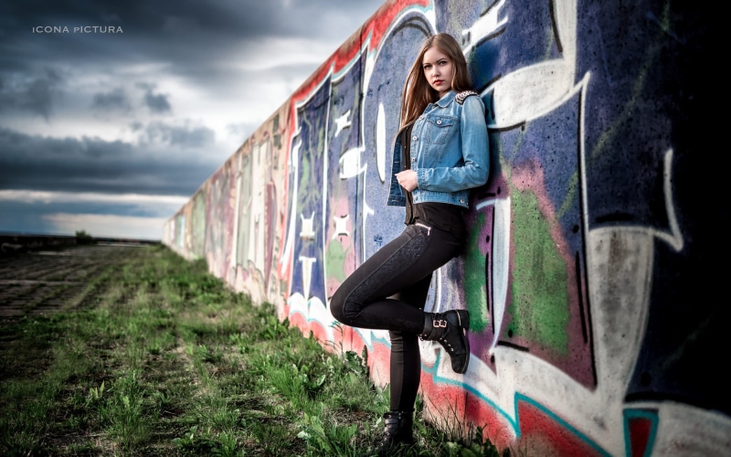 standing, wall, jeans jacket, black shirt, long hair, photography, graffiti, looking at viewer, black pants, zipper, blonde, 500px, jeans, black boots