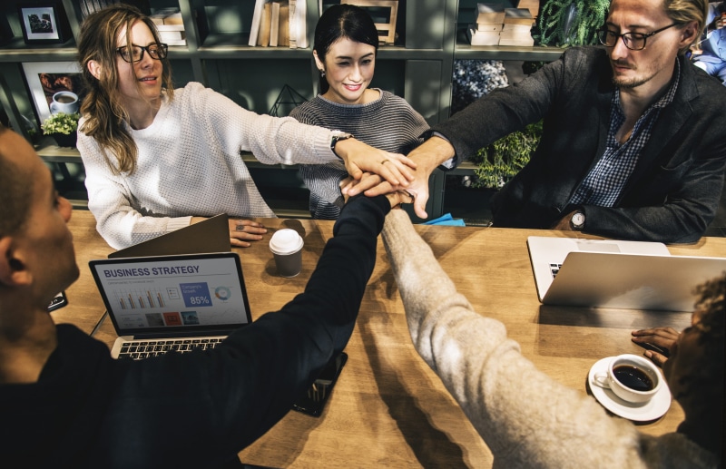 hands, occupation, indoors, young women, meeting, group, males, women, diverse, technology, office, forming, table, team, connection, digital device, communication