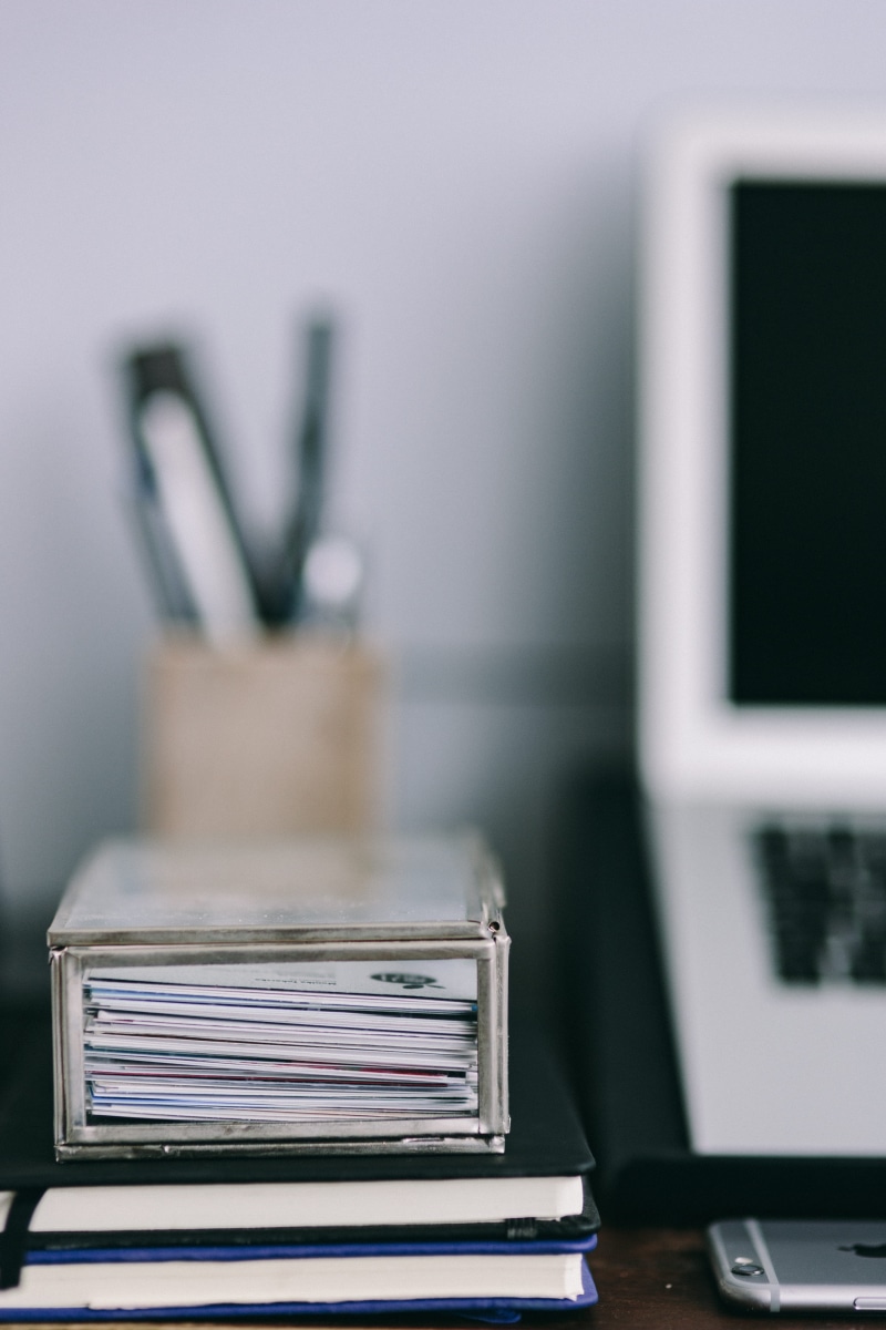 phone, book, desk organizer, wooden desk, table, desk, laptop, Elegant, day, large group of objects, business cards, apple macbook, publication, Macbook