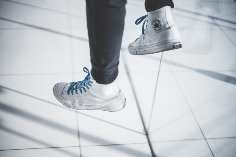 jumping, human leg, outdoors, soil, wearing, human foot, sweater, sneaker, veins, body part, shoes, sock, lifestyles, cardigan, tile, men, white, running shoe