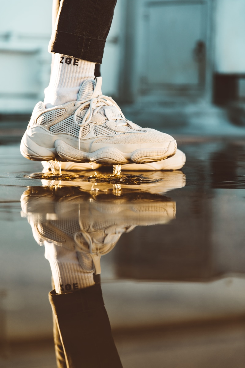 person, footwear, white, floor, human body part, human, running shoe, reflection, day, sport, tied up, body part, apparel, human limb, human hand, selective focus