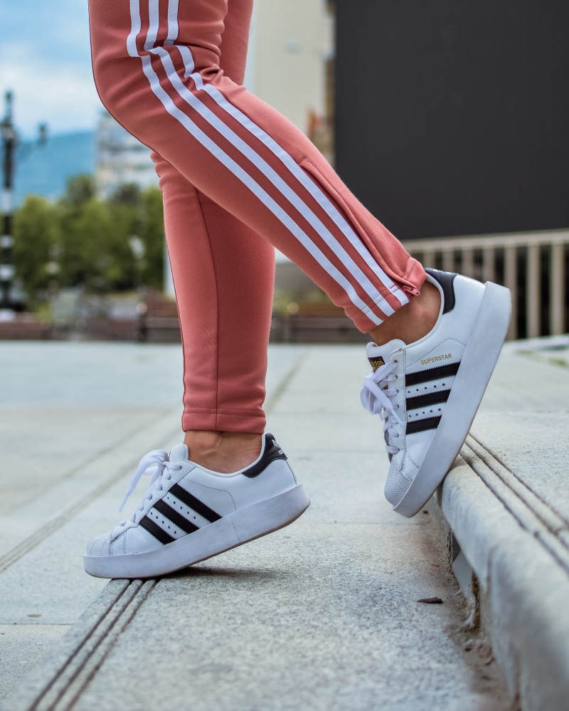 people, canvas shoe, footpath, wear, adidas, real people, superstar, shoes, white, high heel, clothing, human, lifestyles, product, person, apparel, focus on foreground