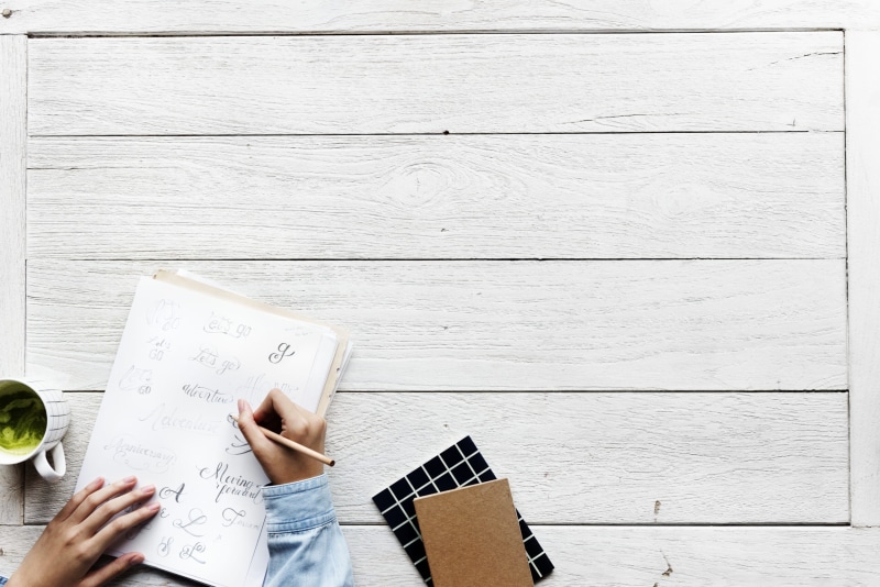 writer, lettering, calligraphy, writing, design, work, coffee, flat lay, real people, human hand, pen, wood - material, cafe, working, stationery, paper