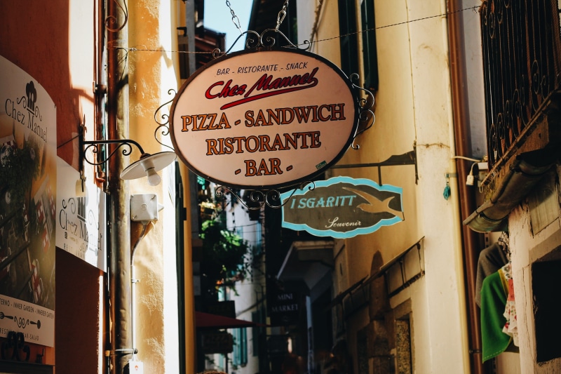 building exterior, manual, island, italy, town, outdoors, isola dei pescatori, information sign, street, sandwich, pizza, 4K, script, information, canopy