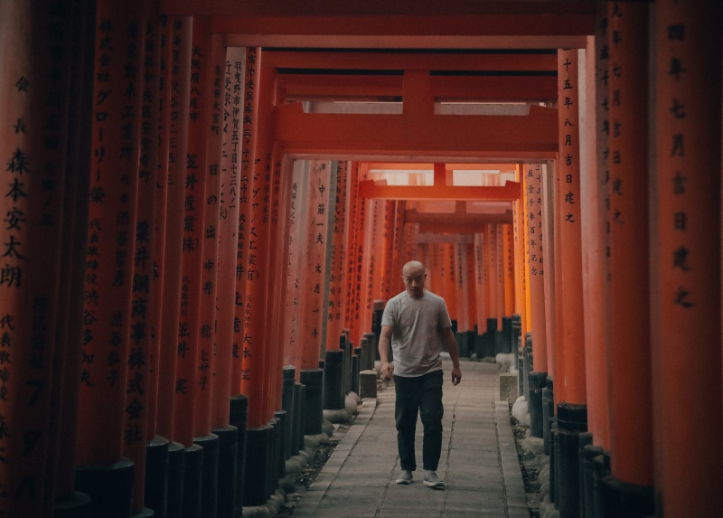 pillar, person, column, built structure, architecture, religion, architectural column, corridor, asphalt, clothing, shrine, walkway, temple, in a row, shoe