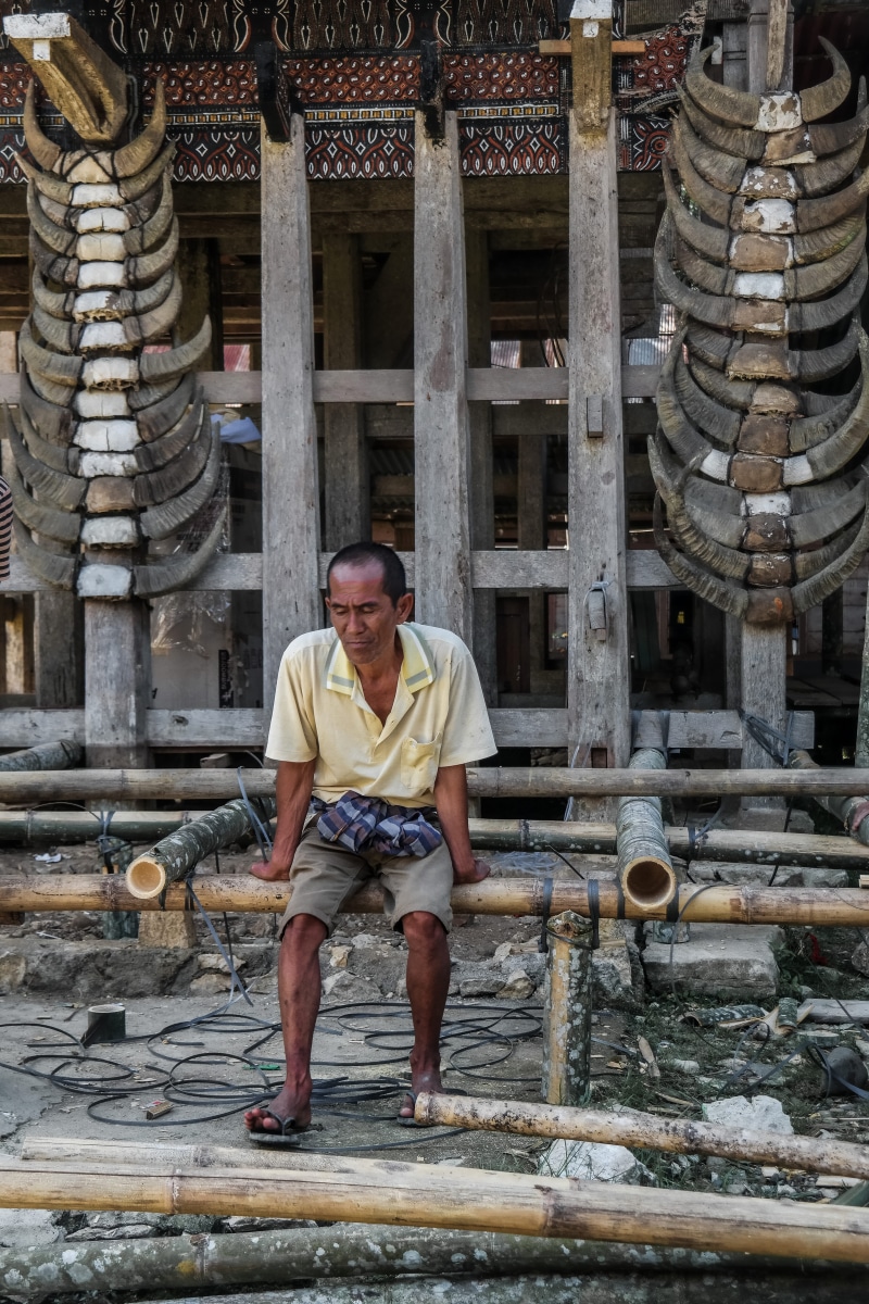 toraja, clothing, pants, sitting, history, place of worship, standing, built structure, person, spirituality, shorts, construction, rest, full length, front view