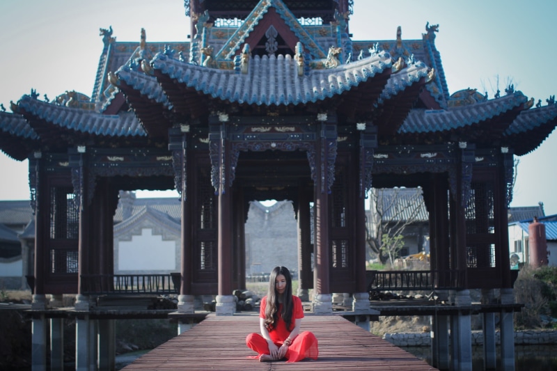 portrait, near, building exterior, asia, sitting, spirituality, outdoors, one person, real people, architecture, leisure activity, lifestyles, red grace