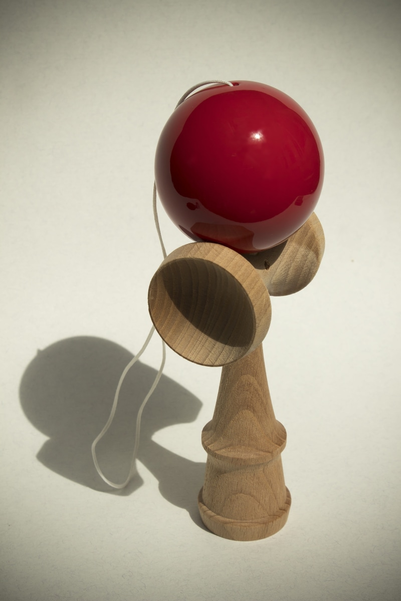 toys, white background, table, 5K, no people, shadow, sphere, kendama, self-defense weapon, red, indoors, wall - building feature, group of objects, play