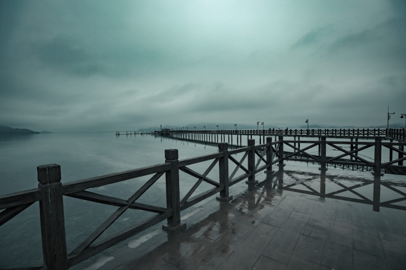 building, storm, pier, concrete, waterfront, tranquility, path, railing, crypt, dusk, boardwalk, cloud - sky, water, handrail, bridge, no people, beauty in nature