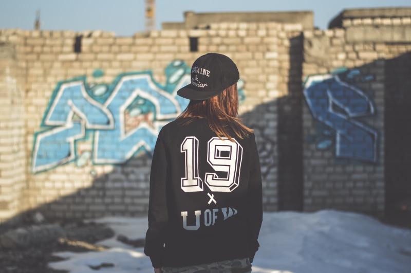 person, sunlight, daytime, architecture, graffiti, woman, jacket, blue, girl, 4K, concrete, focus on foreground, lifestyles, three quarter length, wearing