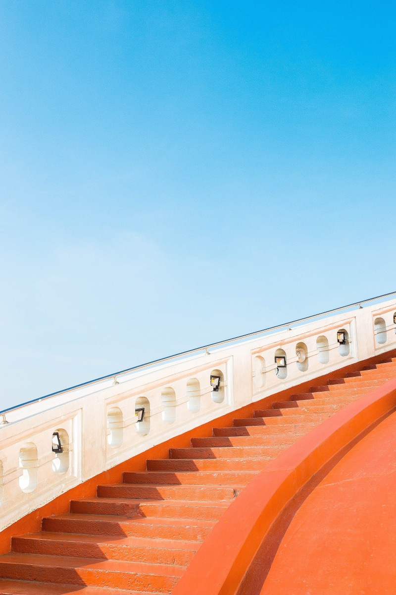 commercial area, no people, transportation, banister, blue, clear sky, orange color, sunlight, faith, land vehicle, minimalist, historic place, railing