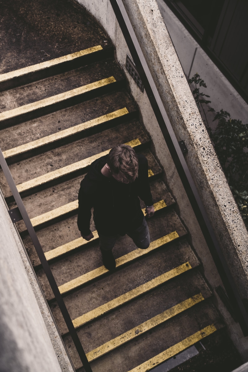 depression - sadness, leisure activity, handrail, sadness, railing, men, human, lifestyles, one person, coat, apparel, staircase, rail transportation, outdoors