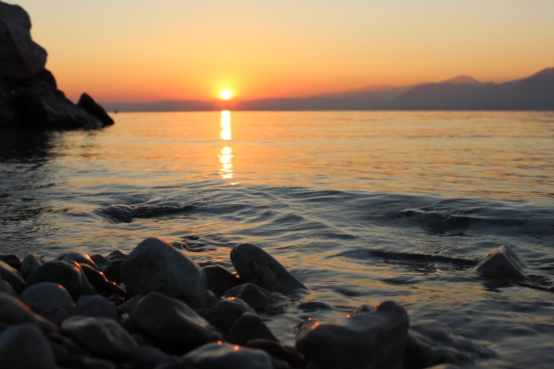 lake, solid, horizon over water, non-urban scene, rock - object, water, land, garda, sun, italia, sunrise, blue, outdoors, rock, calm, nature, horizon