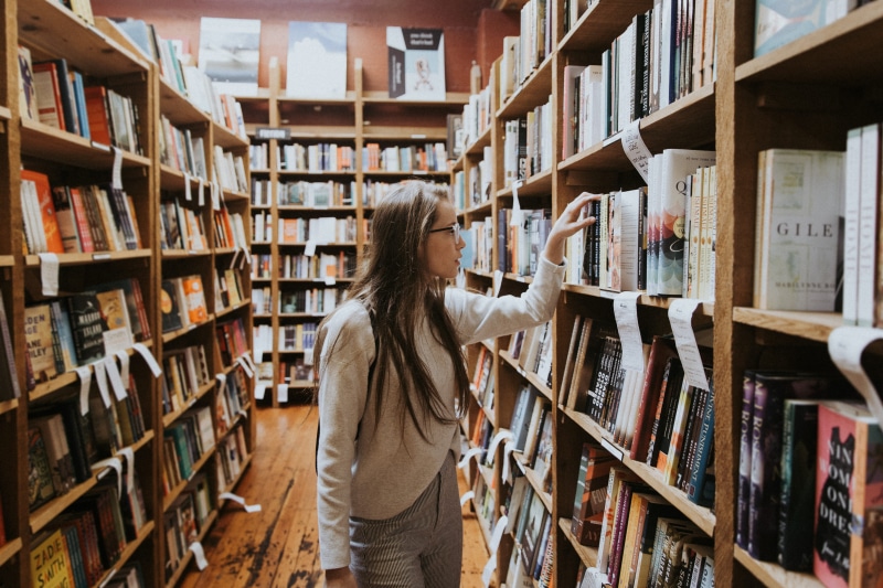 4K, bookshelf, woman, bookstore, searching, choosing, publication, indoors, holding, looking, libary, browse, adult, book shop, bookshop, shelf, hairstyle