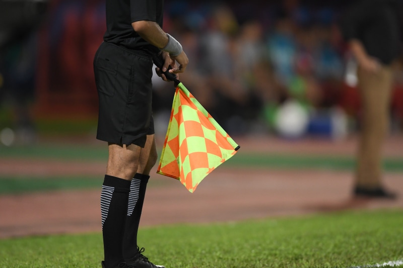 outdoors, referee, field, match, focus on foreground, day, one person, goal, sideline, people, real people, 5K, incidental people, casual clothing, holding