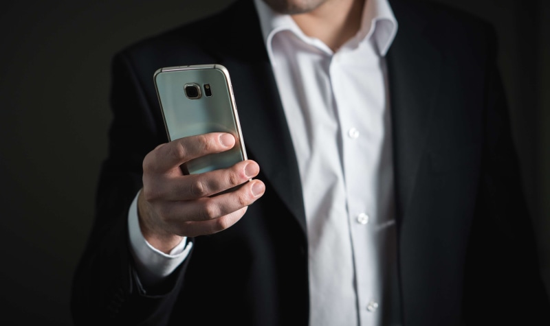 adult, busy, technology, black, formalwear, indoors, suit, portable information device, businessman, men, holding, smart phone, black background, business person
