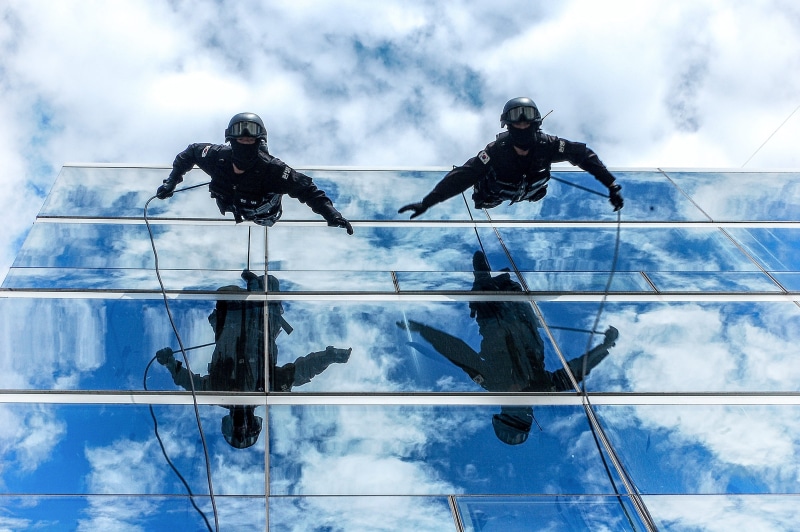 adult, architecture, togetherness, clouds, low angle view, two, building, low angle shot, sport, people, full length, adventure, cloud - sky, ropes, wall