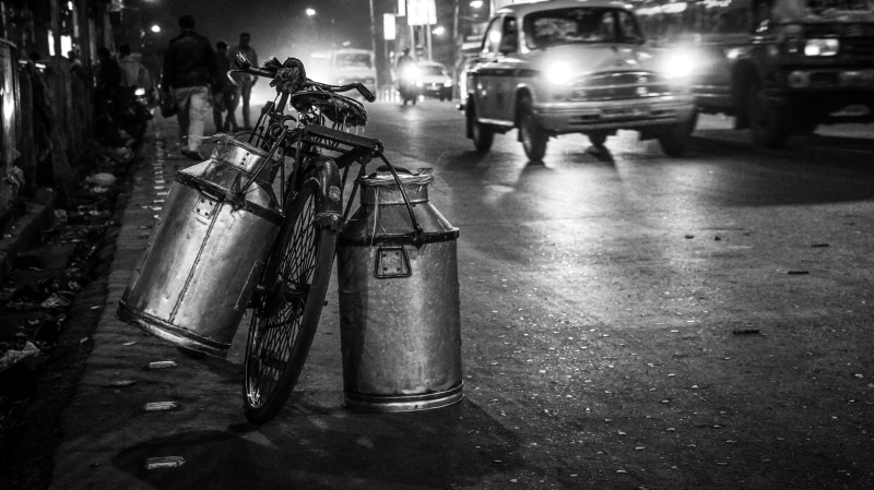 black and white, bicycle, land vehicle, india, city street, wet, roadside, real people, motor vehicle, milk cans, rain, city, 4K, people, street, transportation