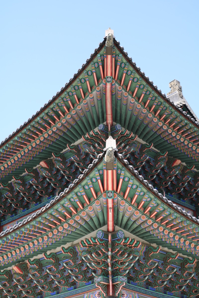 clear sky, art, spirituality, day, place of worship, outdoors, sky, tourism, gyeongbok palace, roof, art and craft, nature, traditional, religion, ornate