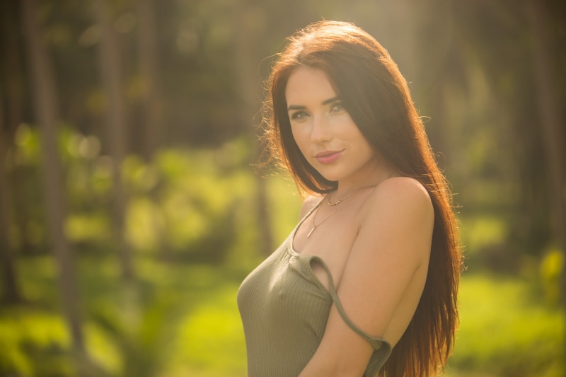 women, 2K, Niemira, women outdoors, sunlight, looking at viewer, portrait, brunette, necklace, depth of field, lens flare, model, smiling, tank top, long hair