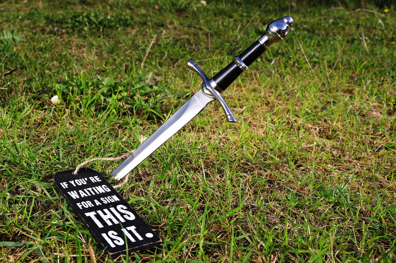weapon, equipment, field, outdoors, tool, close-up, plant, bicycle, western script, sign, text, day, grass, characters, growth, no people, nature, symbol