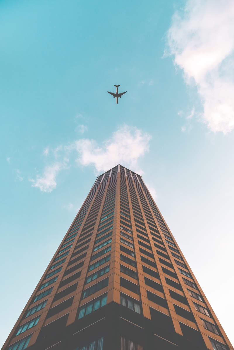 cloud - sky, tall - high, mid-air, airliner, skyscraper, building, landmark, bottom, tower, no people, sky, view, air vehicle, brown, low angle view, aerospace industry