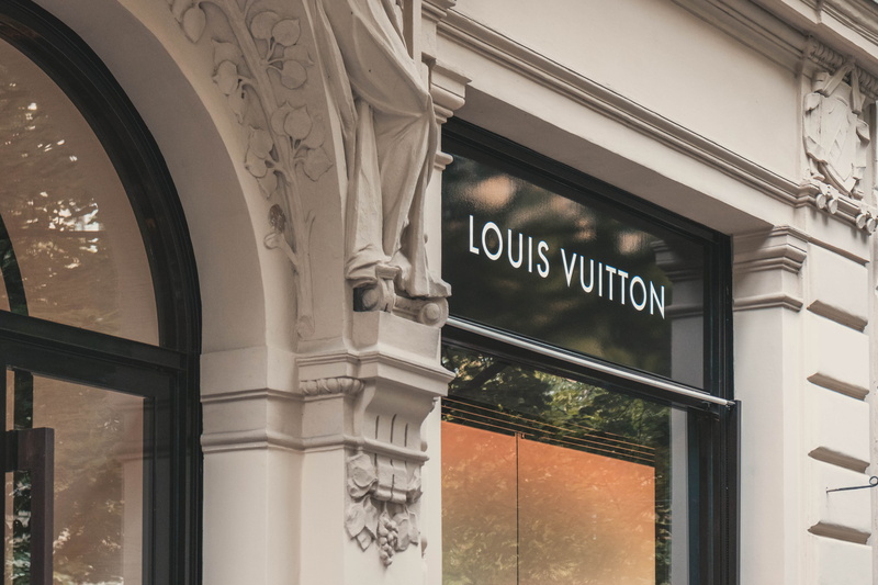 sign, western script, vuitton, window, building, day, travel, communication, signage, architectural column, text, outdoors, architecture, building exterior