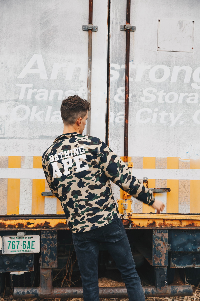 board, sign, leisure activity, brown, standing, young men, man, ape, sweatshirt, one person, lifestyles, text, real people, day, outdoors, wearing, graffiti