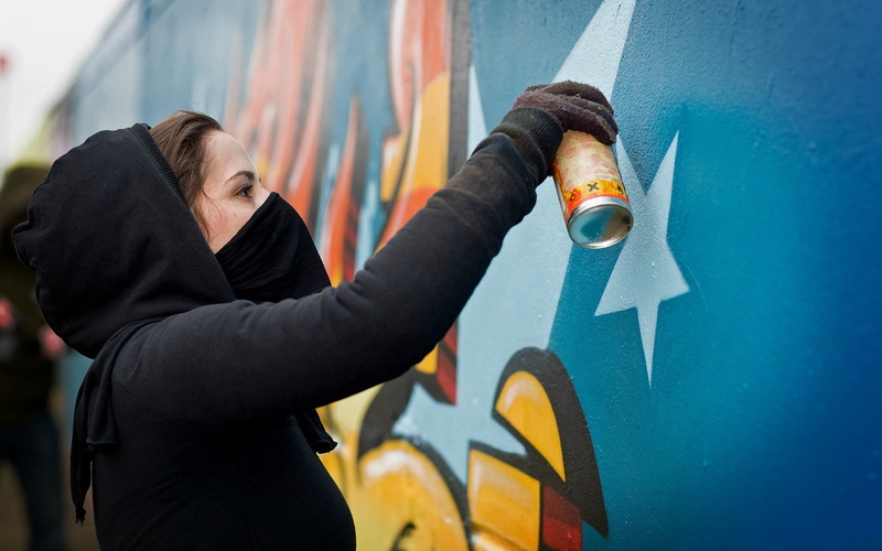 girl, clothing, mask, mural, 2K, paint, architecture, hood - clothing, lifestyles, waist up, urban Scene, holding, spray paint, spray, young Adult, wall