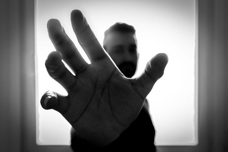 one person, dark, light, body part, aggression, unrecognizable person, gesturing, finger, spooky, man, black-and-white, studio, human hand, focus on foreground