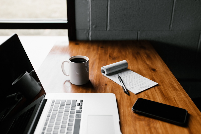 smartphone, wood - material, laptop, black coffee, wooden, computer, macbook, beverage, food and drink, desk, indoors, workplace, pen, keyboard, coffee