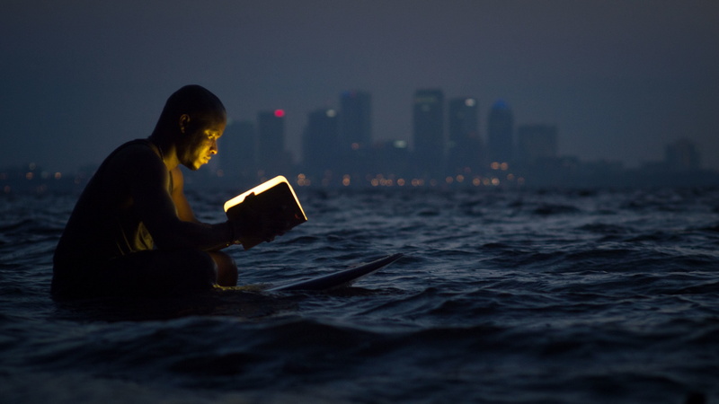profile view, ocean, landscape, building, night, body, skyscraper, urban skyline, building exterior, book, outdoors, reading, surfing, person, blur, buildings