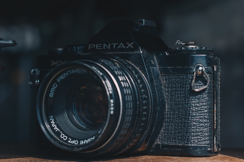 photographic equipment, camera, slr camera, aperture, retro styled, 2K, focus on foreground, close-up, antique, indoors, no people, table, single object