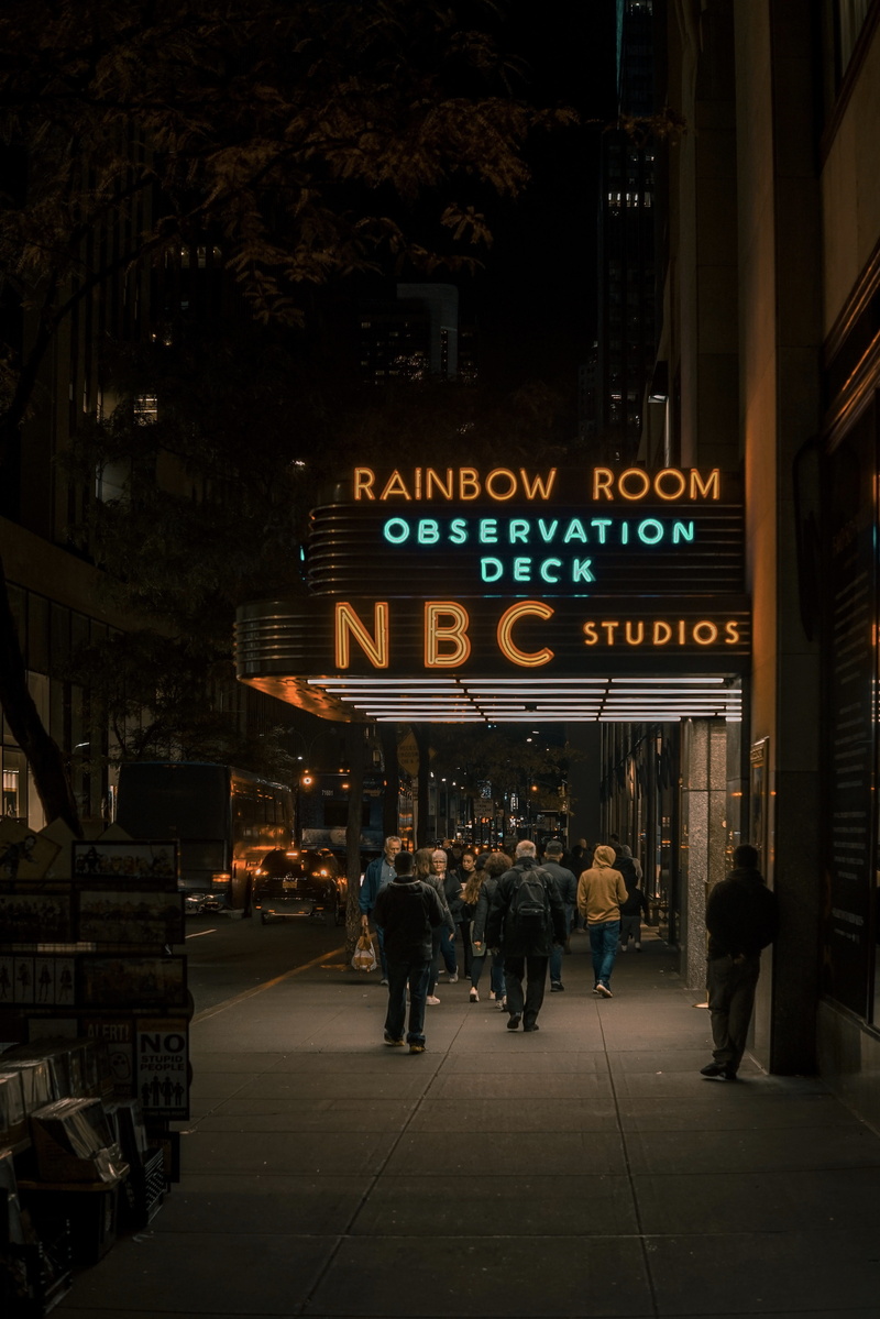 illuminated, city life, non-western script, real people, nbc, information, sleeve, urban, building, building exterior, text, communication, clothing, walking