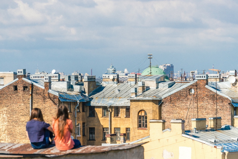 friend, built structure, sitting, cloud, outdoors, roof, two people, males, sky, adult, front, buildings, girls, blue, sunny, rooftop, gray, city, two