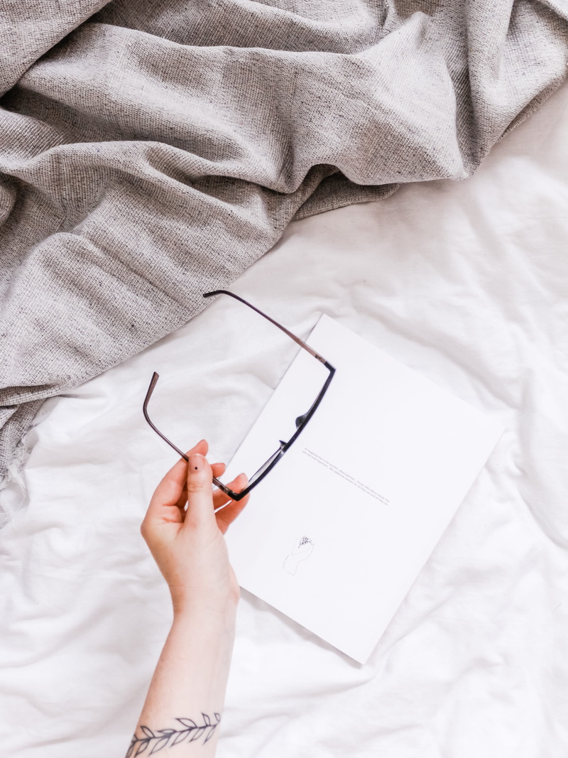 hand, lifestyles, pattern, pen, real people, stain, heel, linen, pillow, eyeglasses, diary, frame, sheet, handwriting, lying down, page, black, human limb