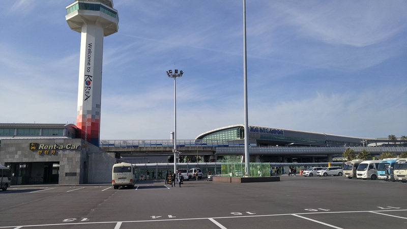 day, built structure, outdoors, jeju international airport, transportation, building exterior, sign, road, cloud - sky, street, modern, sky, travel, incidental people