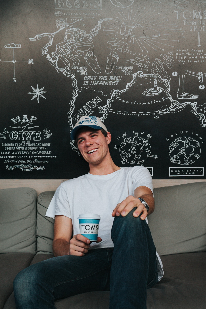 text, board, t, gray, couch, young adult, chair, person, emotion, blackboard, one person, sit, wearing, painted, cup, three quarter length, portrait, man