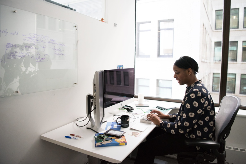 sitting, whiteboard, indoors, design professional, screen, front, office, waist up, women, one person, room, side view, adult, device, desk, casual clothing