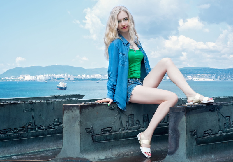woman in blue, model, stone, sitting, one young woman only, hairstyle, woman, shirt, one woman only, clouds, real people, concrete, blue denim, sport, hair