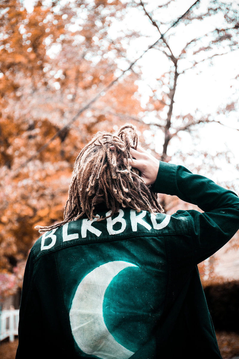man, hairstyle, canon, forest, black, day, focus on foreground, dreads, bright, nature, 5K, standing, hair, one person, waist up, male, holding, jacket