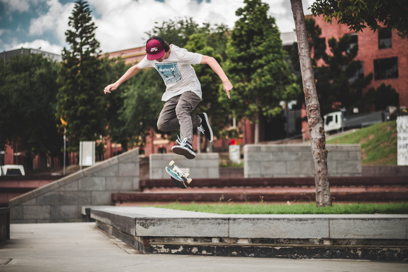 arms raised, full length, architecture, cap, leisure activity, day, skating, daytime, outside, one person, jumping, tree, outdoors, skateboard, skateboarding