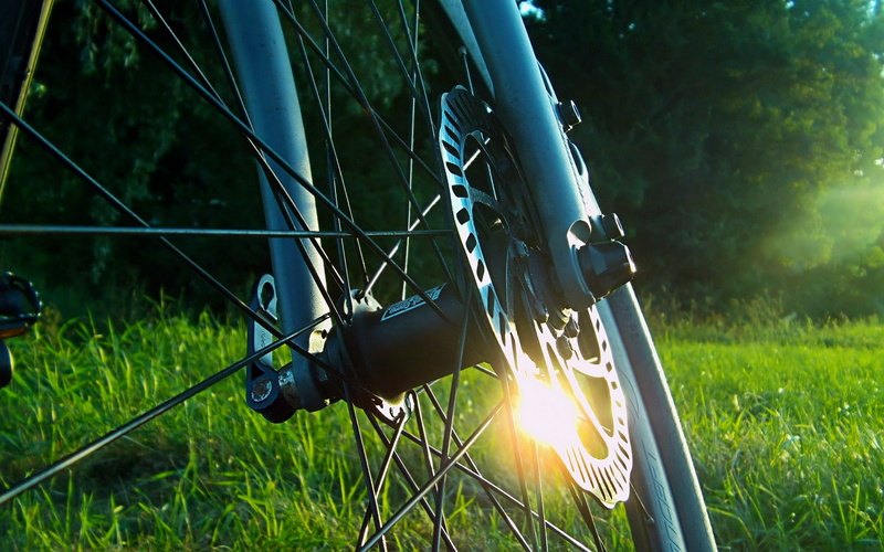equipment, wheel, mountain bikes, focus on foreground, lens flare, grey, day, field, sunlight, sky, metal, bicycle, rim, nature, plant, green color, spoke