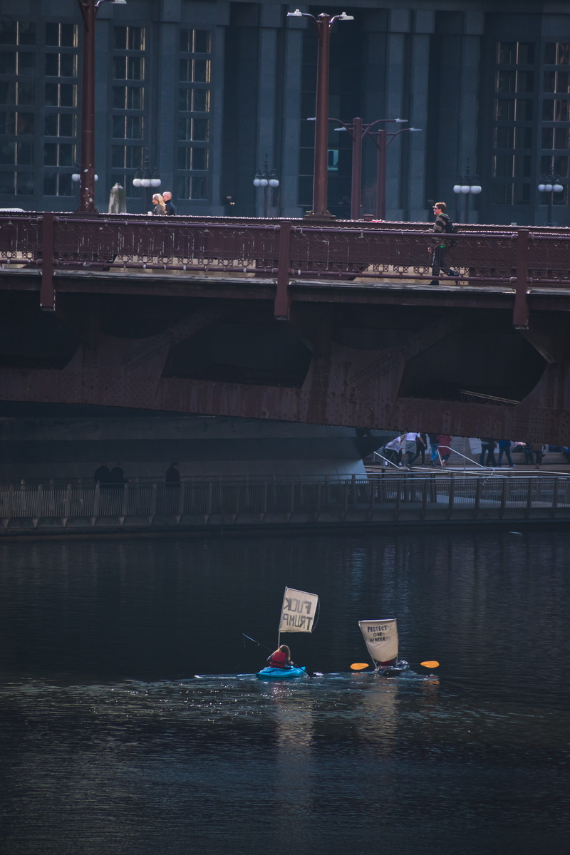 woman, bridge, city, transportation, photography, protest, built structure, waterfront, kayak, day, sign, river, connection, nature, chicago, water, building exterior